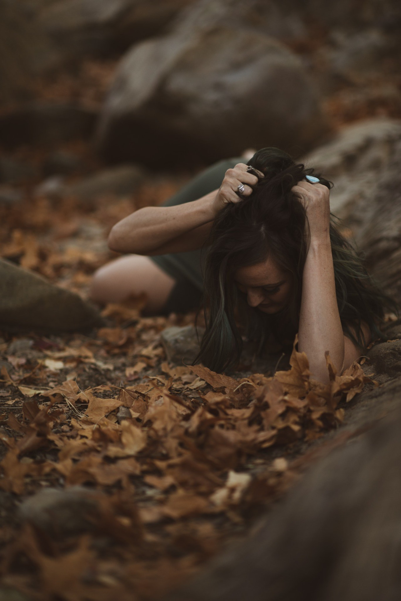Woman lying among fallen leaves with her hands in her hair