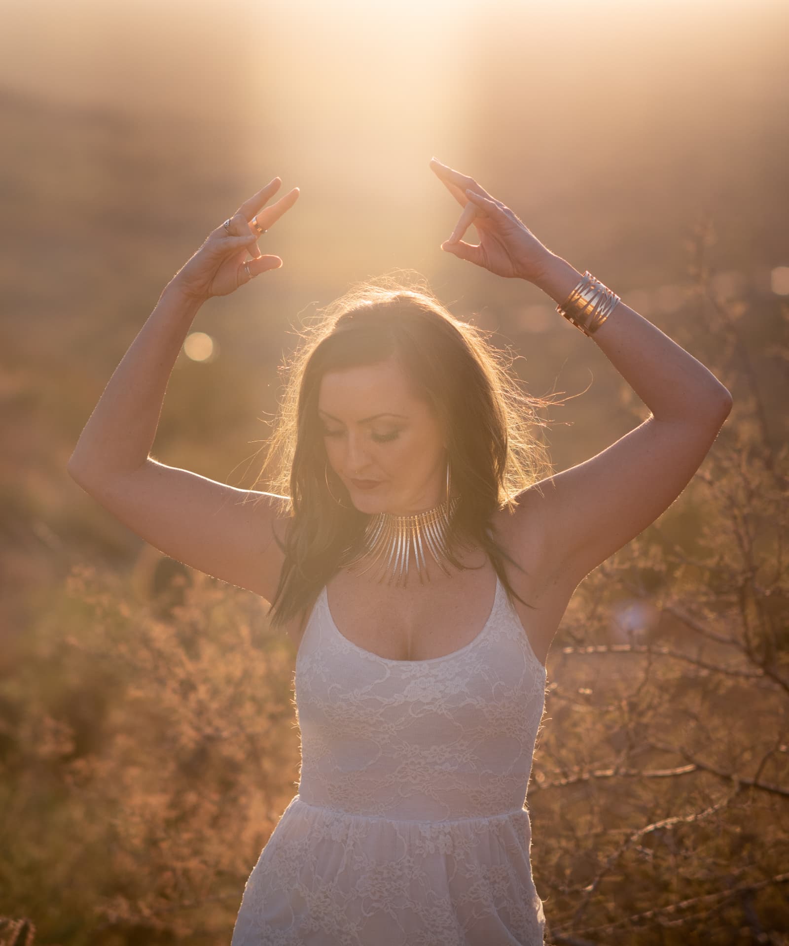 Jenna with both hands raised in golden-hour light