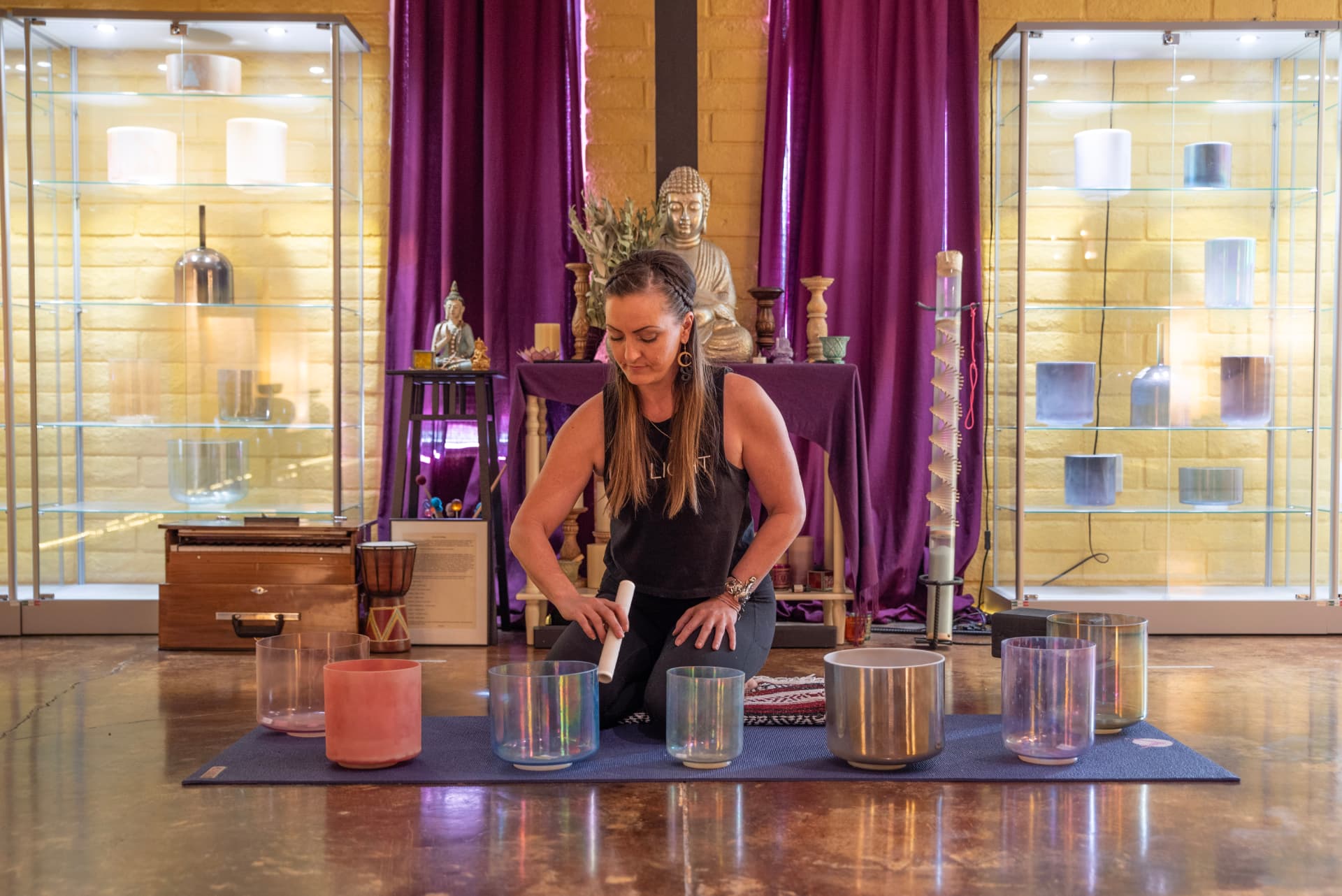 Jenna seated behind a row of crystal singing bowls in the Surya Yoga studio