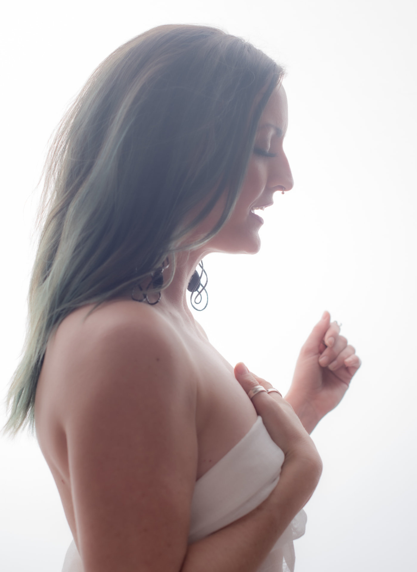Jenna in profile with hands resting near her heart against a bright background